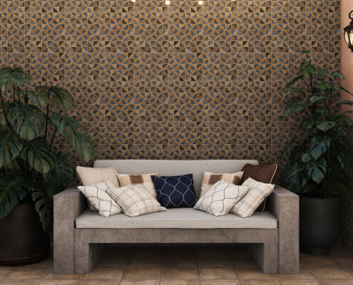 Ambiente moderno y acogedor con un sofá gris, cojines de diferentes diseños y una pared decorada con un mosaico Gres patrones geométricos dorados.