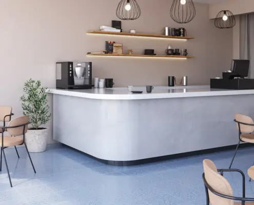 Espacio de cafetería moderno con barra blanca y piso en cerámica azul tipo terrazo, ejemplo de diseño interior funcional y sostenible